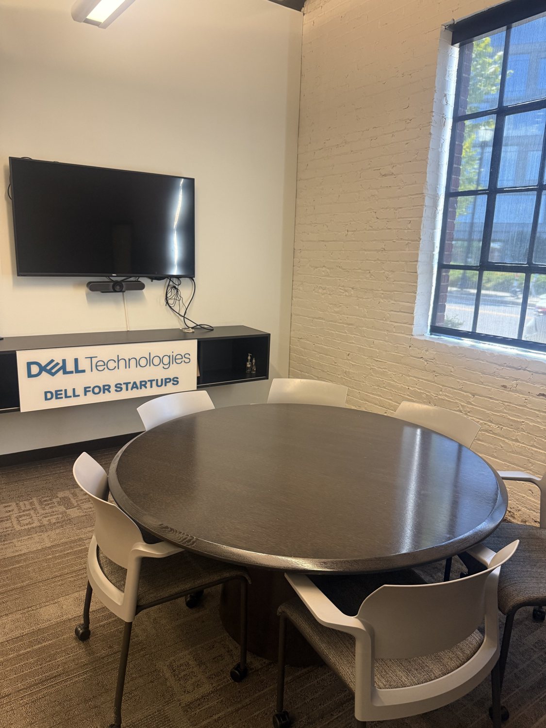The same wall today with a blank TV and a Dell Technologies sign.